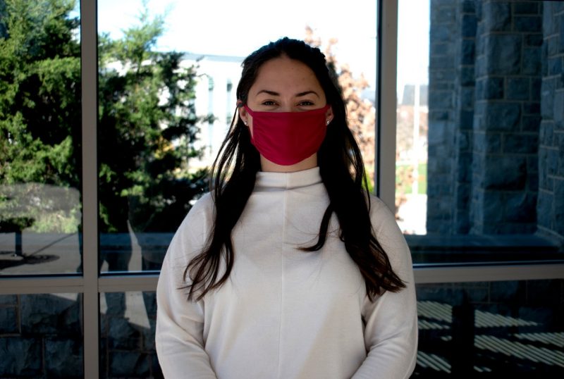 Christine Faunce, wearing a face mask per COVID protection guidelines, stands in front of the Life Sciences 1 building.